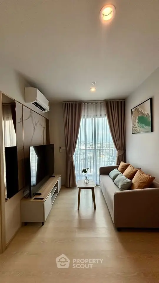 Modern living room with large TV, cozy sofa, and city view through window.