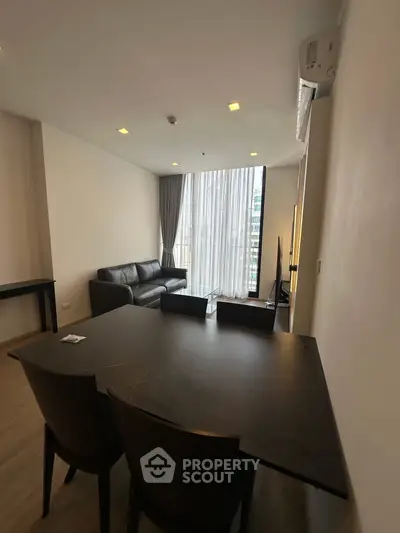 Modern living room with sleek furniture and large windows offering city views.