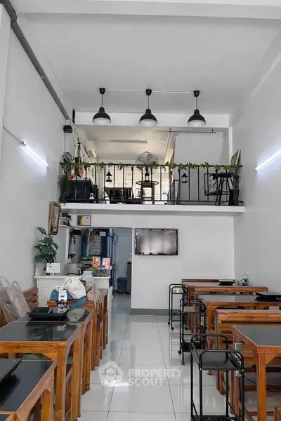 Chic modern cafe interior with stylish wooden furniture and mezzanine seating area.