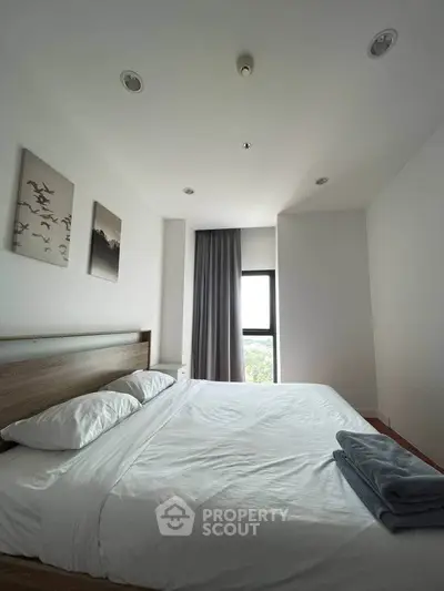 Spacious bedroom with modern decor and large window offering natural light.
