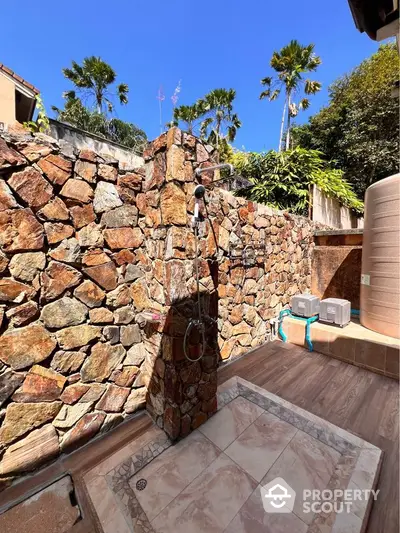 Stunning outdoor shower area with stone wall and tropical landscaping