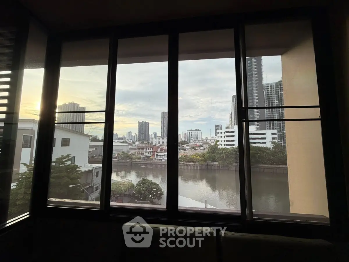 Stunning cityscape view from a modern apartment window overlooking a serene river.