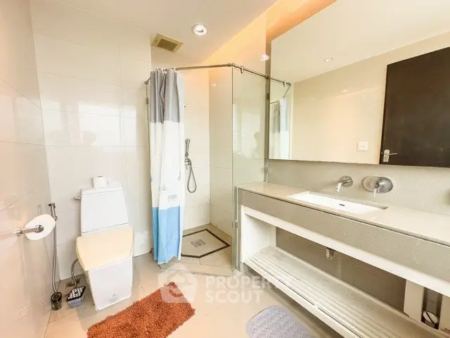 Modern bathroom with glass shower and sleek vanity in luxury apartment.