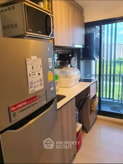 Compact modern kitchen with stainless steel appliances and ample cabinet space, featuring a large window with a serene view.