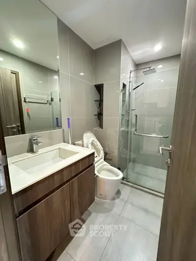 Modern bathroom with sleek fixtures and glass shower enclosure in a contemporary apartment.
