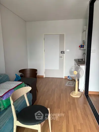 Cozy living room with wooden flooring and compact kitchenette, ideal for modern urban living.