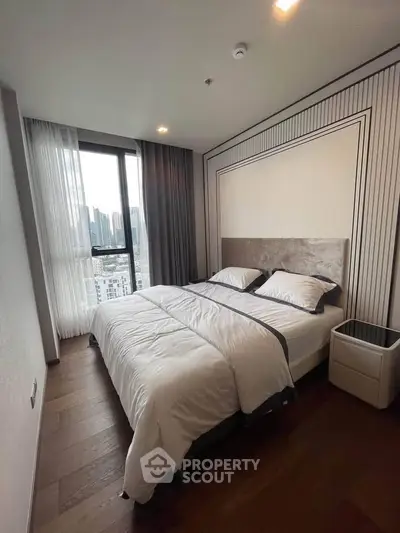Modern bedroom with city view, featuring elegant decor and large windows for natural light.