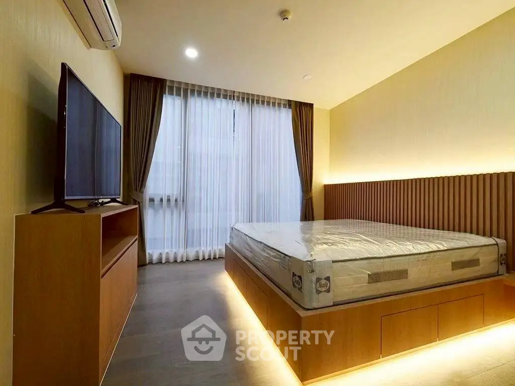 Modern bedroom with sleek design, featuring a large bed, ambient lighting, and a wall-mounted TV.