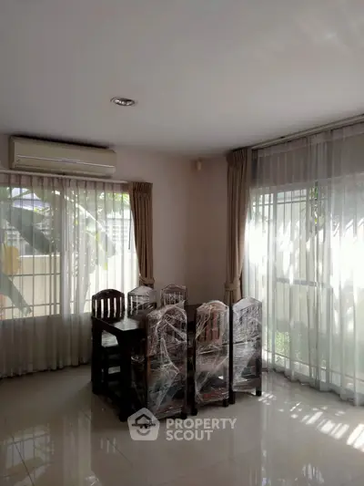Bright dining area with natural light and air conditioning, featuring a wooden table and chairs.