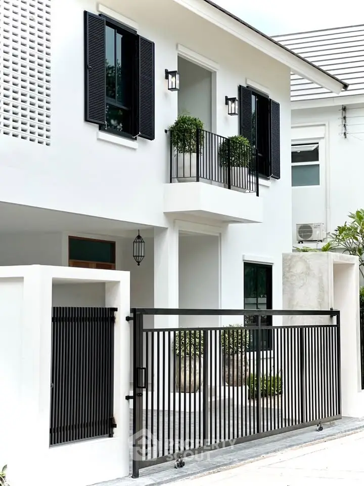 Modern white house exterior with black accents and gated entrance.