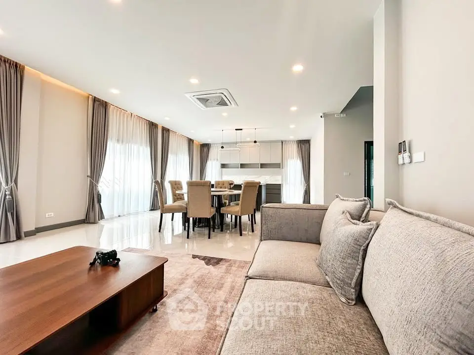 Spacious modern living room with elegant dining area and natural light.