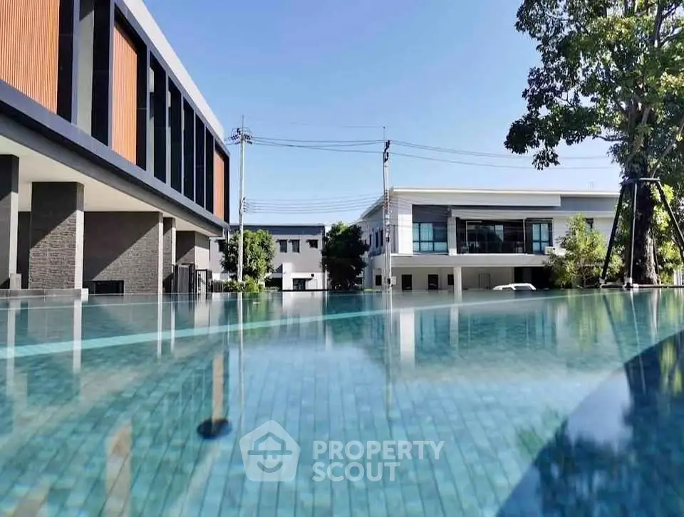 Luxurious modern building with serene pool view and lush greenery, perfect for relaxation and leisure.
