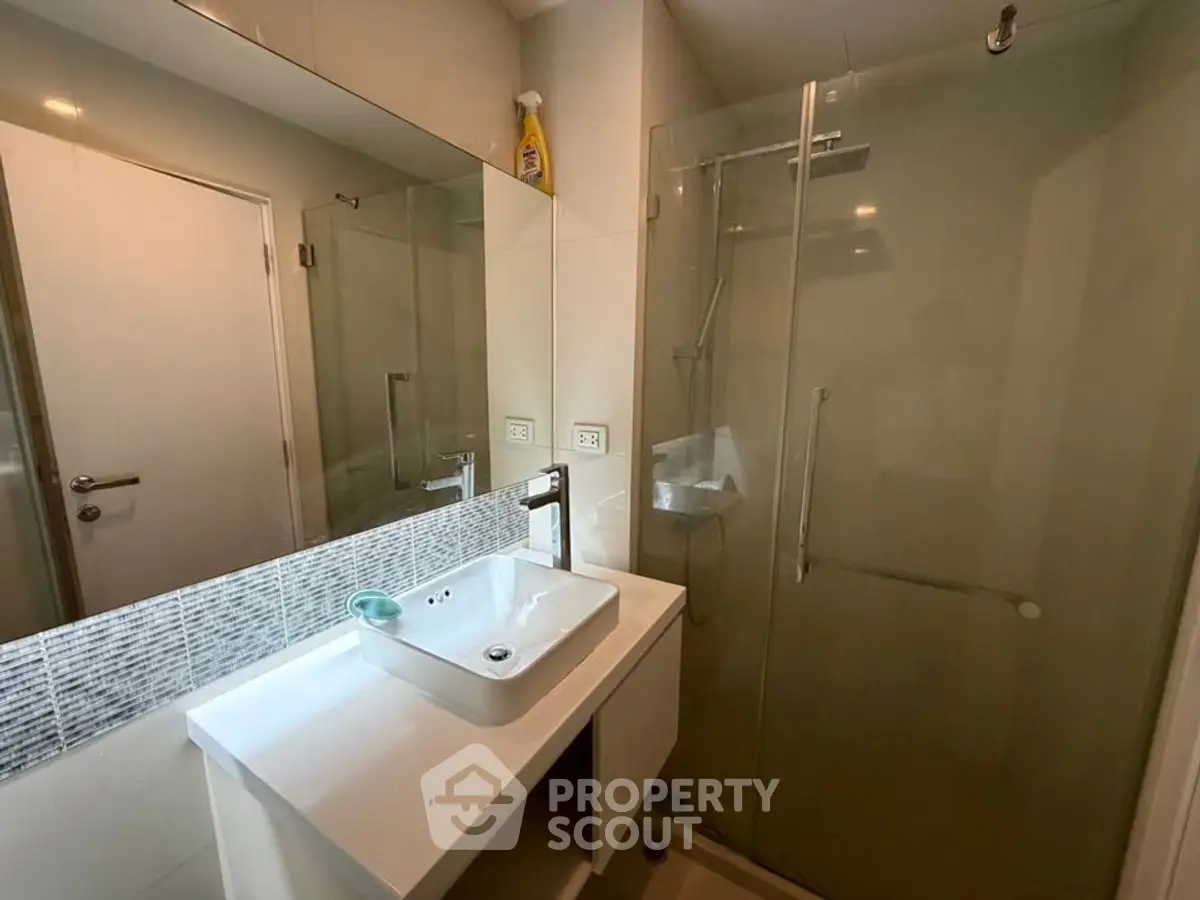 Modern bathroom with glass shower and sleek vanity in contemporary home.