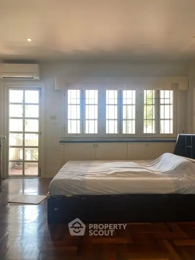 Spacious bedroom with large windows and wooden flooring