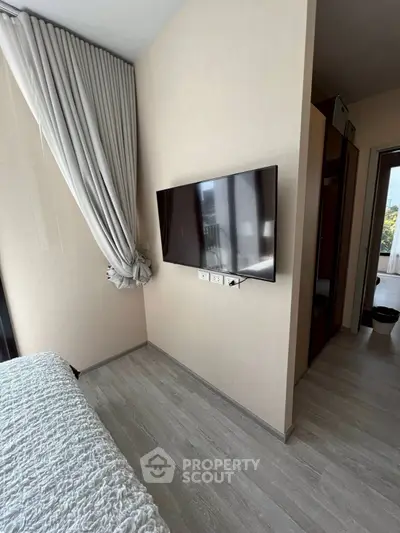Modern bedroom with wall-mounted TV and elegant curtains in a stylish apartment.