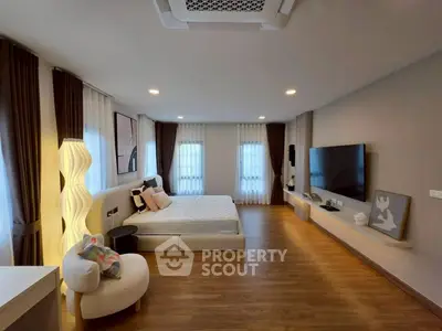 Spacious modern bedroom with elegant decor and large TV setup