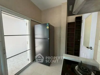 Modern kitchen with sleek black fridge and gas stove, featuring a closed layout and tiled flooring.