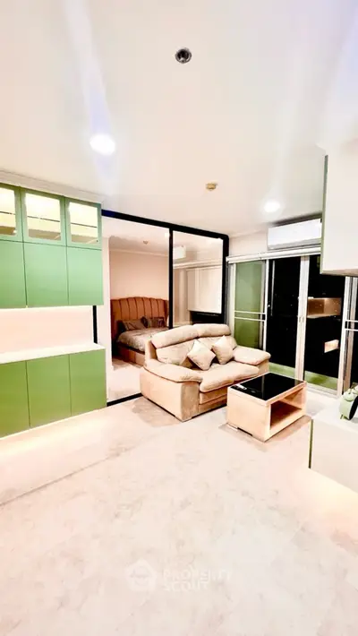 Modern living room with stylish green cabinets and cozy beige sofa, featuring a sleek open layout and elegant decor.