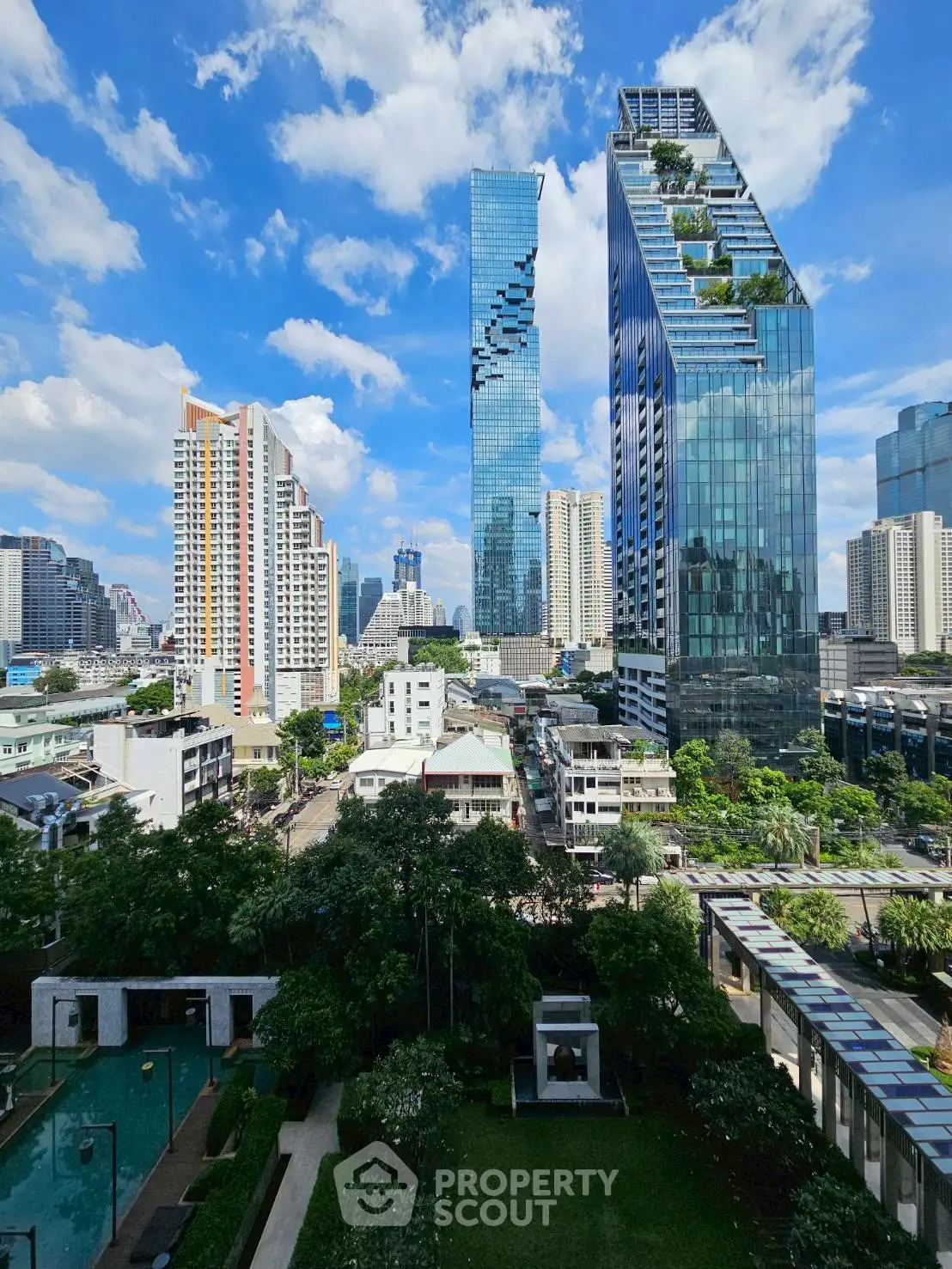 Stunning cityscape view with modern skyscrapers and lush green gardens, showcasing urban luxury living.