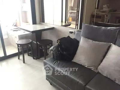 Modern living room with stylish gray sofa and cozy dining area in a well-lit apartment.