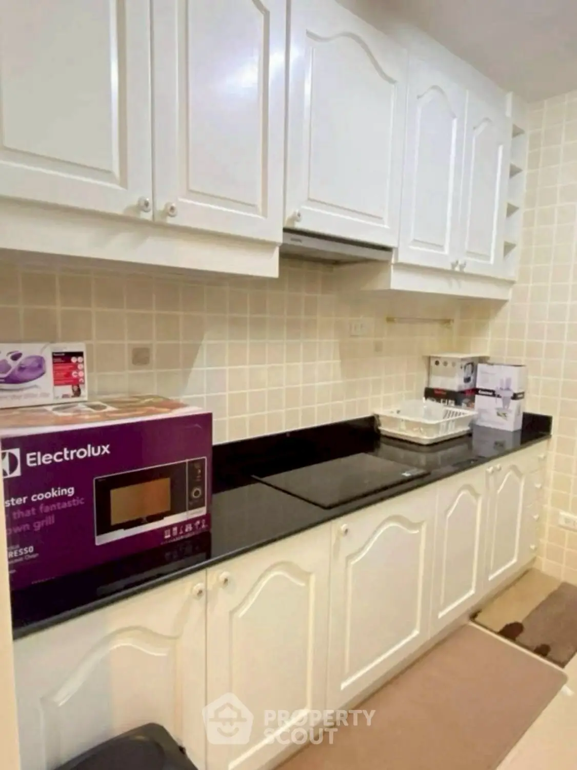 Modern kitchen with white cabinets and black countertop featuring Electrolux microwave.