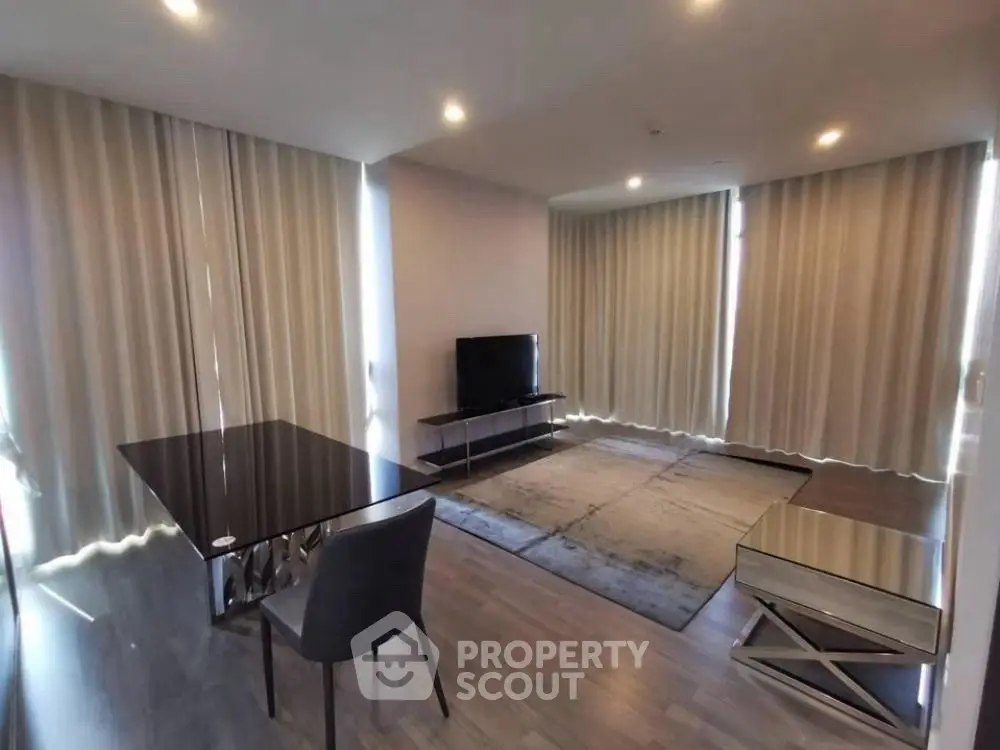 Modern living room with sleek furniture and large windows with curtains.