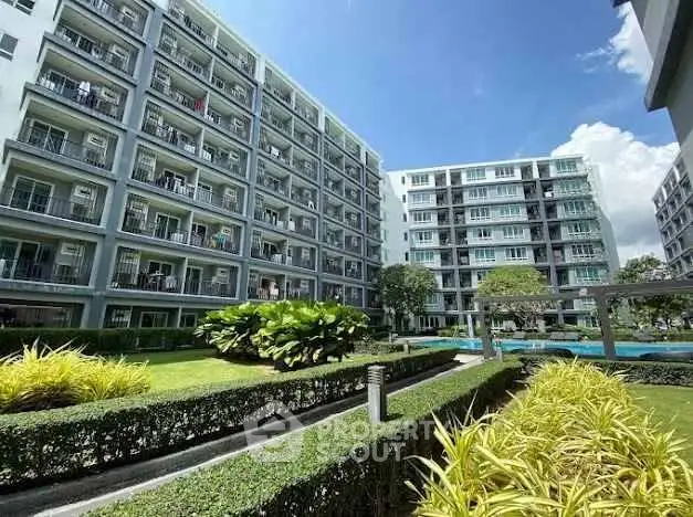 Modern apartment complex with lush gardens and clear blue sky