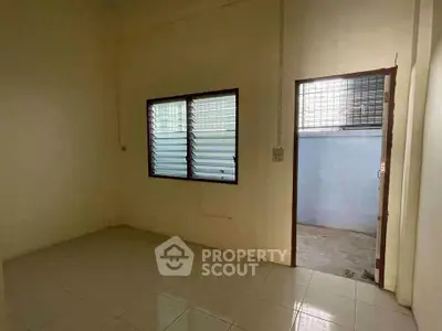 Spacious empty room with tiled floor and large window, ideal for customization.