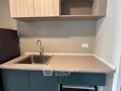 Modern kitchen with sleek cabinetry and stainless steel sink, perfect for compact living spaces.