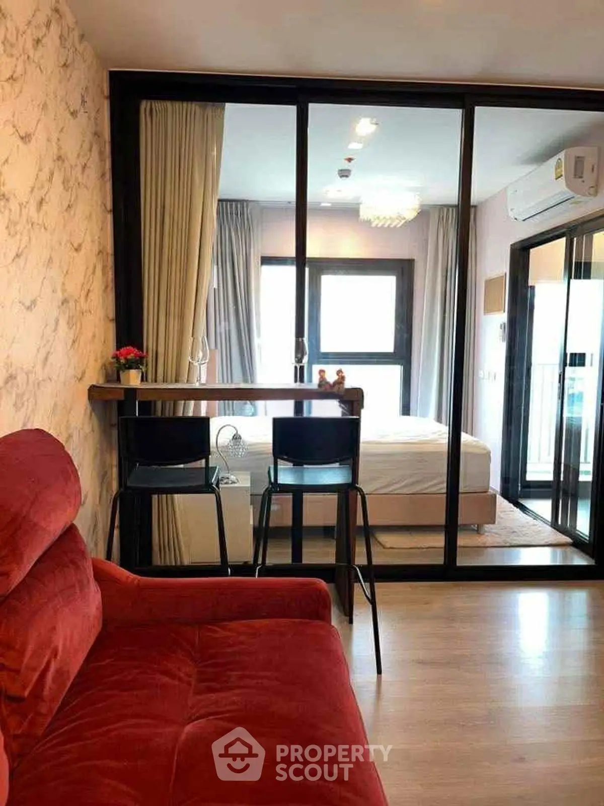 Modern apartment interior with red sofa and glass partitioned bedroom