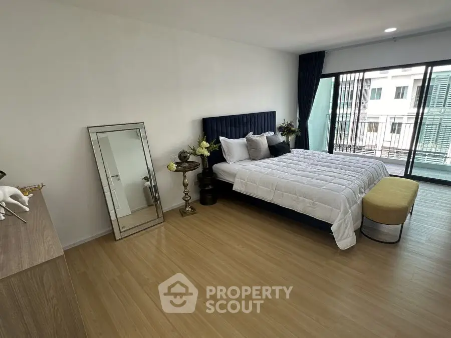Spacious modern bedroom with elegant decor and large window view.
