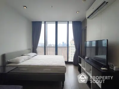 Modern bedroom with city view, featuring large windows and sleek furnishings.