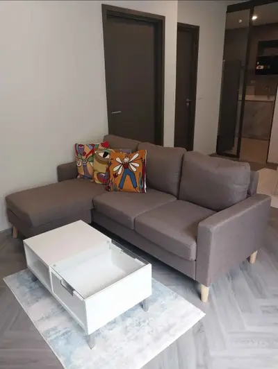 Modern living room with stylish gray sofa and colorful cushions, featuring a sleek white coffee table on a chic rug.