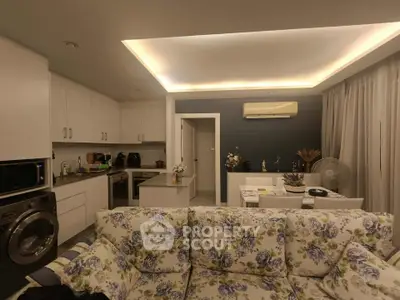 Charming open-layout living room with floral sofa and modern kitchen appliances.