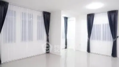 Spacious modern living room with large windows and elegant curtains