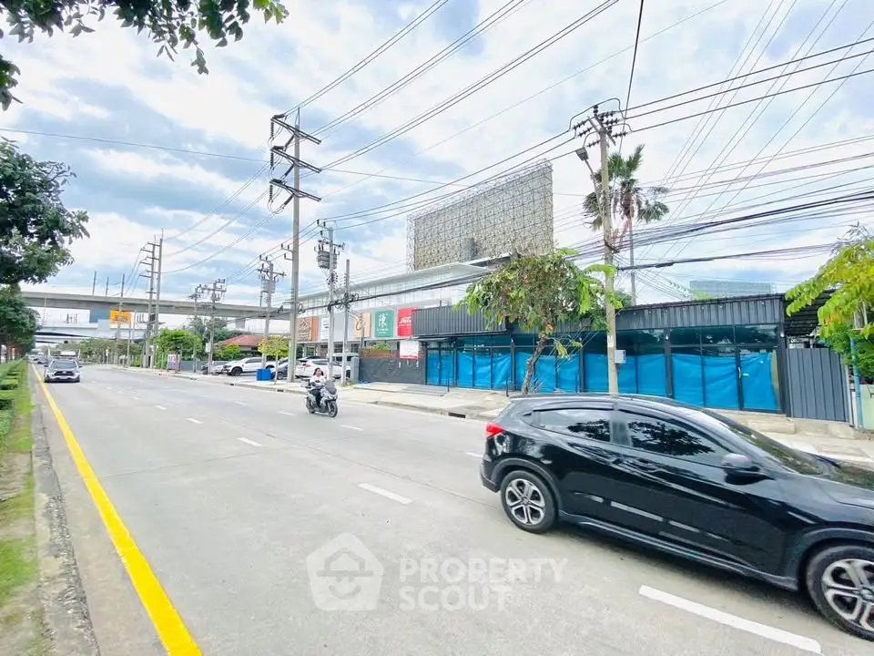 Street view of commercial building with modern facade and ample parking space.