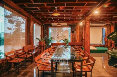 Stunning wooden interior dining area with large glass table and lush greenery.