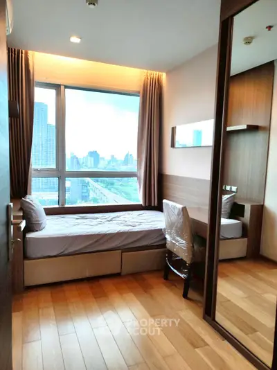 Modern bedroom with city view, wooden flooring, and stylish furnishings in a high-rise apartment.