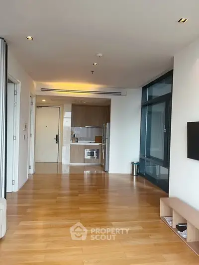 Spacious modern apartment with open layout and sleek kitchen design, featuring wooden flooring and ample natural light.