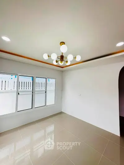 Bright empty room with modern chandelier and large window, perfect for customization.