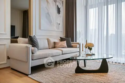 Elegant living room with modern sofa and glass coffee table, featuring chic decor and natural light.