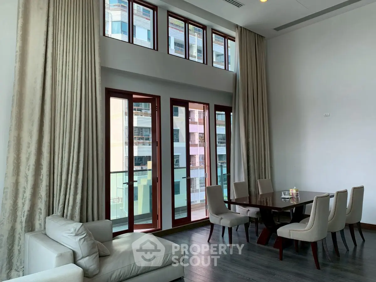 Elegant high-ceiling living room with large windows and stylish furniture
