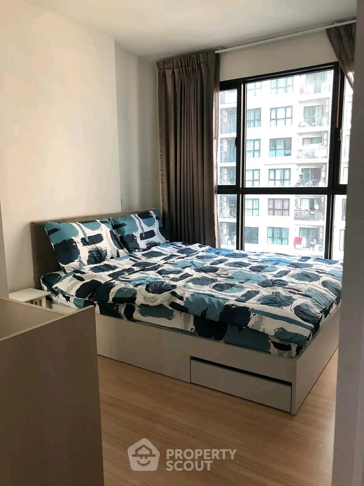 Modern bedroom with large window and stylish bedding in urban apartment