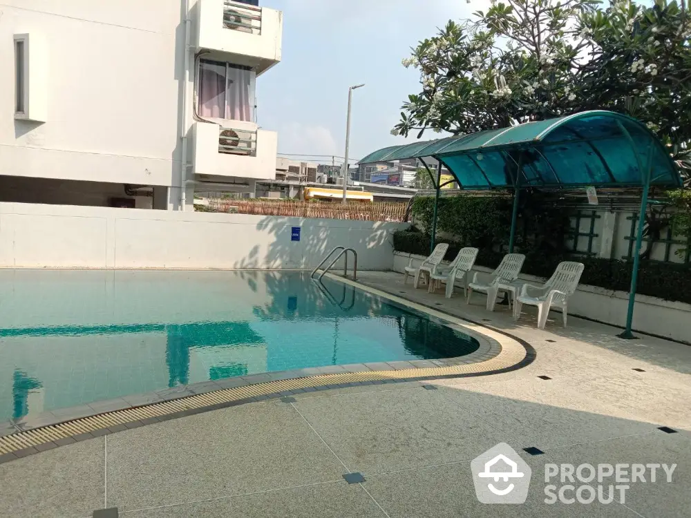 Modern apartment complex with inviting swimming pool and poolside seating area.