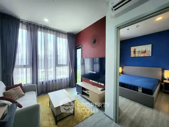 Modern apartment living room with large windows and stylish bedroom view.