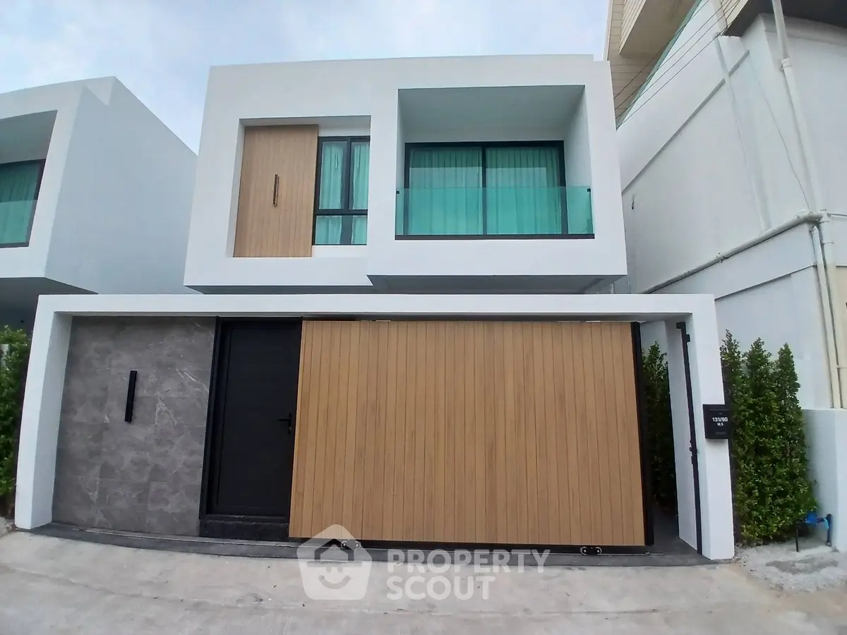 Modern two-story house with sleek design and large windows in a contemporary neighborhood.