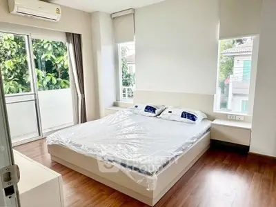 Modern bedroom with large windows and balcony access, featuring a sleek design and natural light.
