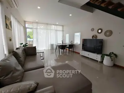 Spacious modern living room with sleek furniture and large windows offering natural light.