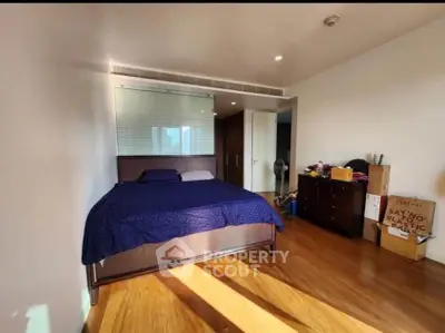 Spacious bedroom with wooden flooring and modern decor in a luxury apartment.