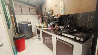 Cozy kitchen with gas stove and washing machine, featuring marble backsplash and ample storage.